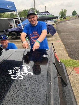 Man pointing to Suave Sauce logo on race car, Rochester NY sponsor